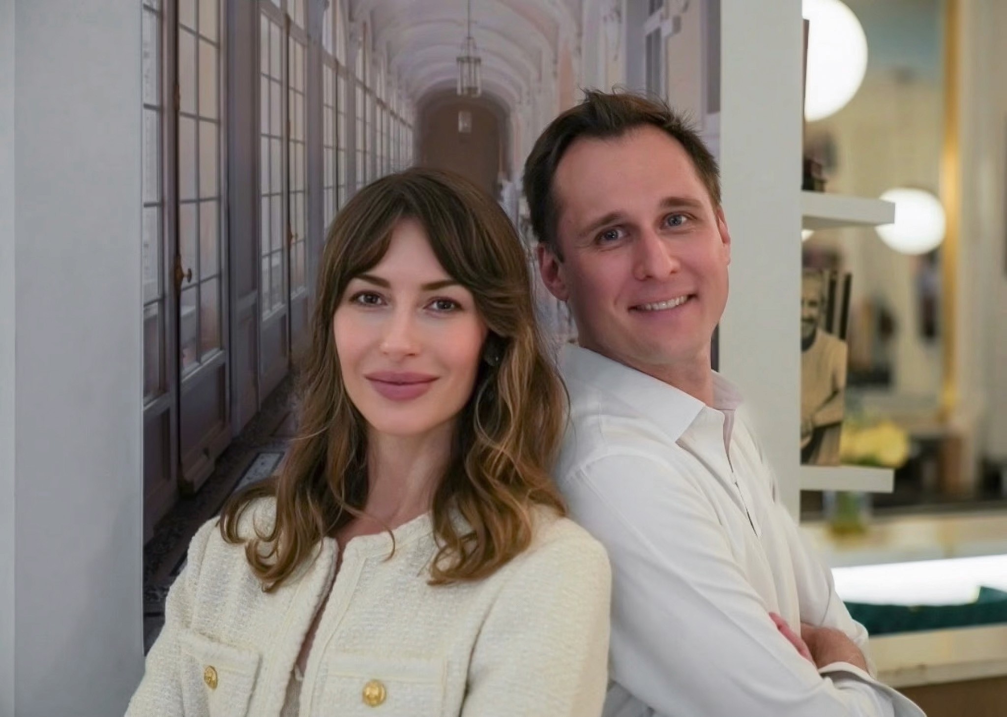 Julien Spiewak and Anna Pyatibratova standing back to back in a bright gallery corridor